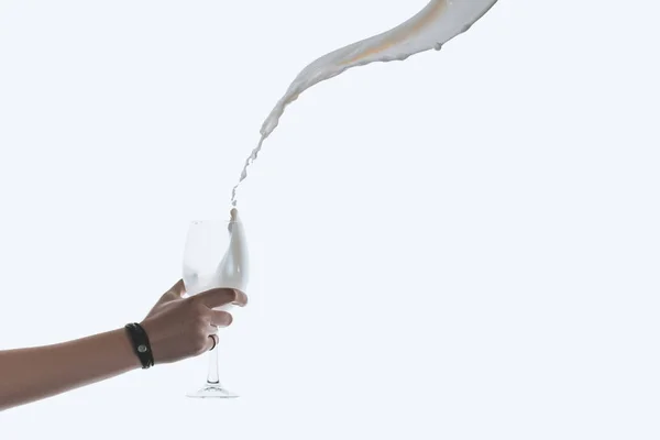 Hand holding glass with splash of milk — Stock Photo, Image