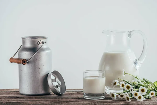 Fresh milk in jugs with flowers — Stock Photo, Image