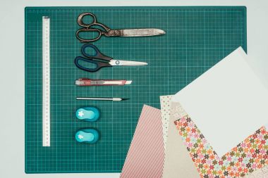 Top view of sheets of paper and scissors with stationery knife for making scrapbooking postcard clipart
