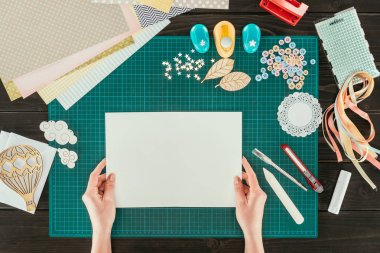 cropped image of woman holding white sheet of paper in hands clipart