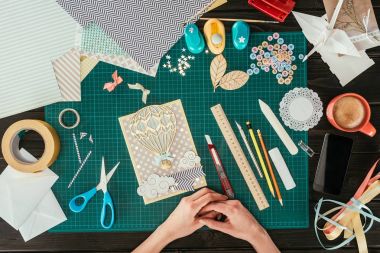 cropped image of designer sitting with scrapbooking handmade postcard at working table clipart