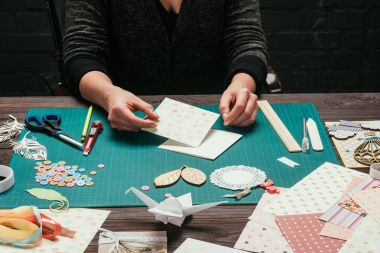 Tasarımcı masada oturan ve scrapbooking kartpostal yapma kırpılmış görüntü