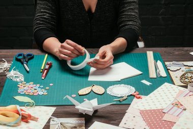 cropped image of designer taking piece of adhesive tape clipart