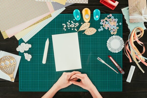 cropped image of designer sitting at table with empty white sheet of paper
