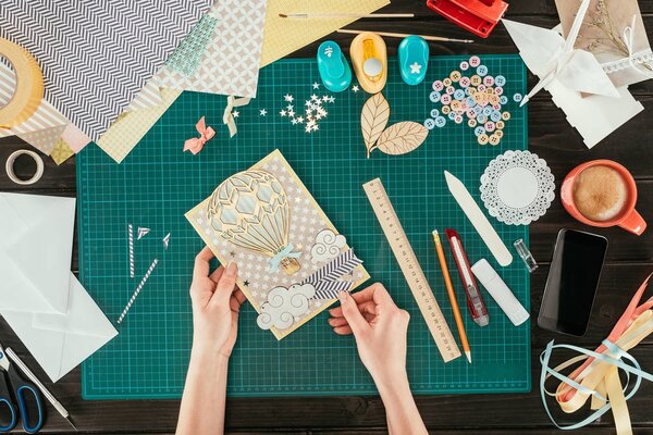 cropped image of artist holding scrapbooking handmade postcard with wooden balloon