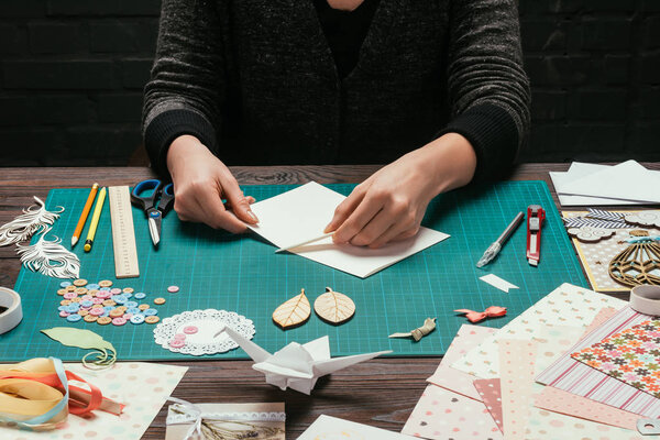 cropped image of designer cutting empty sheet of paper