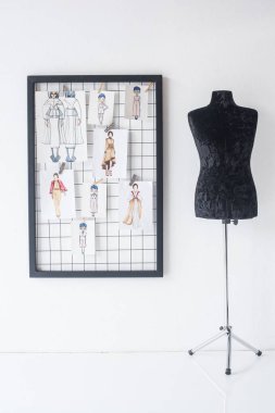 frame with fashion sketches hanged on white checkered background and black mannequin clipart
