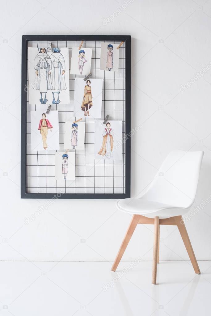 black frame with sketches on wall and chair in white room