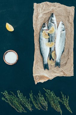 top view of healthy fish with lemon slices on paper on black clipart