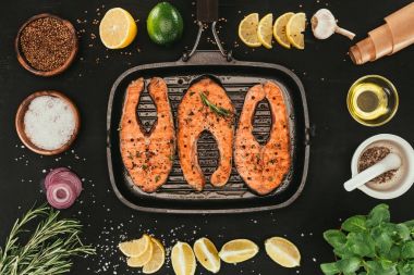top view of salmon steaks on grill and spices on black clipart