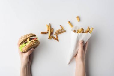 kırpılan hamburger ve kızarmış patates üzerinde beyaz izole kağıt koni ile el görünümünü