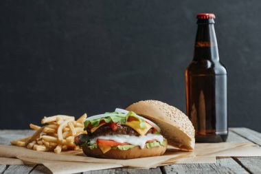 geleneksel ev yapımı hamburger, patates kızartması ve bir ahşap masa üzerinde kagit üzerinde bira