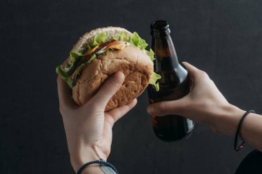 hamburger ve bira şişe tutan kişinin görünümü kırpılmış