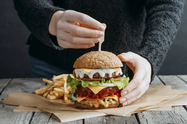 Przycięte Widok Kobiecych Rąk Duże Smaczne Cheeseburger Frytki Papier Pieczenia — Zdjęcie stockowe