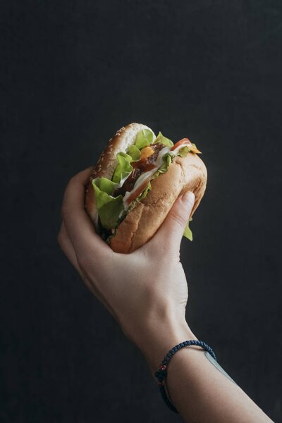 cropped view of person holdong tasty cheeseburger