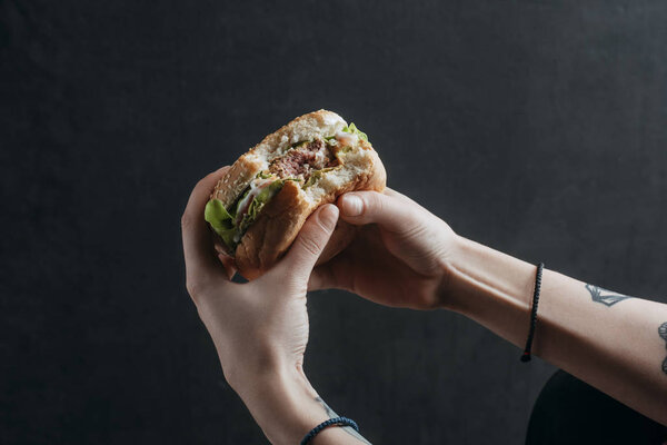 cropped view of person eating tasty hamburger