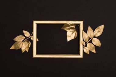 top view of golden photo frame and leaves isolated on black clipart