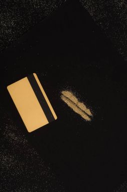 top view of golden credit card and powder lines isolated on black clipart