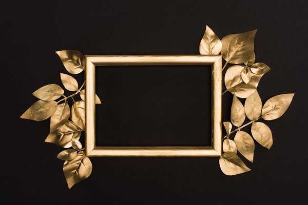 top view of golden photo frame and leaves isolated on black