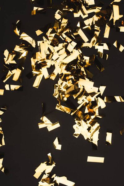 close up view of sparkling golden confetti isolated on black