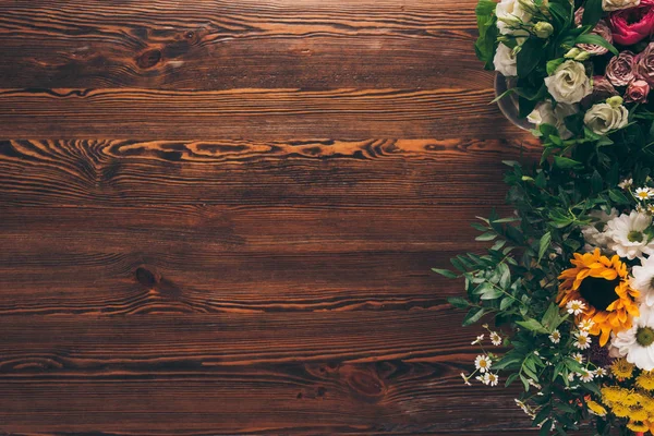茶色の木製のテーブルに異なる花のトップ ビュー — ストック写真