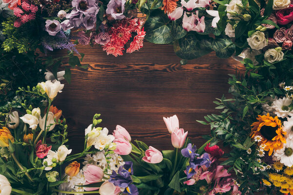 top view of frame of colored flowers on wooden table