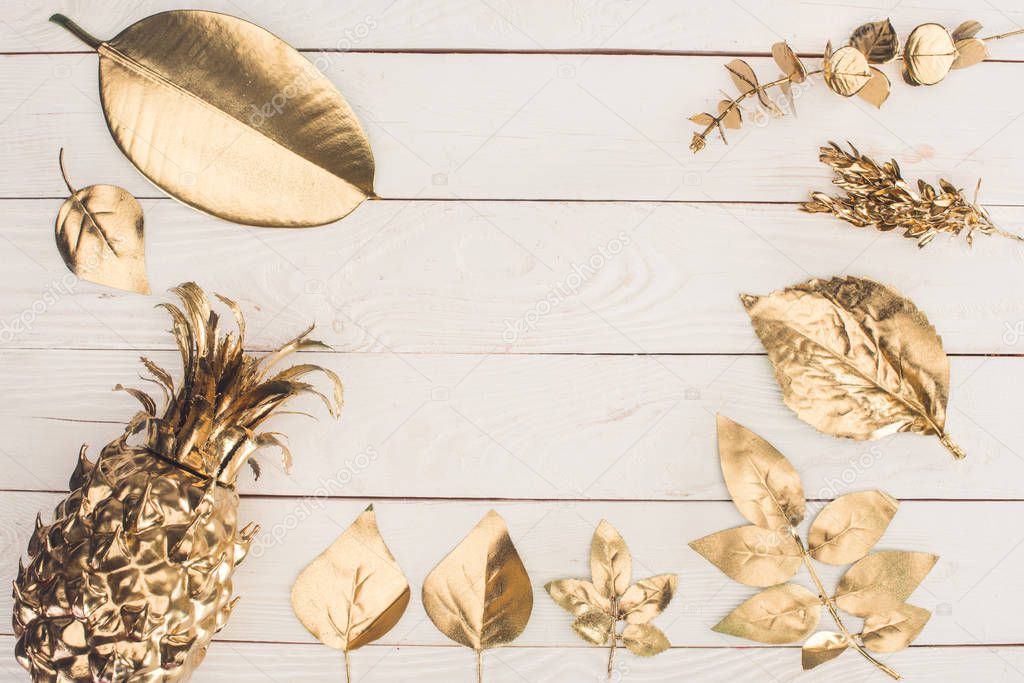 top view of set of various golden leaves and pineapple on wooden surface