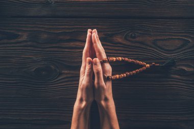 cropped image of woman holding rosary and praying at table  clipart