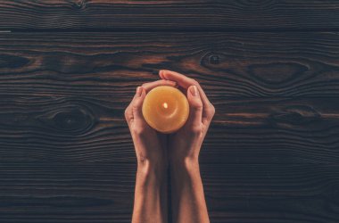 ahşap masa üstünde mum tutan kadın kırpılmış görüntü 
