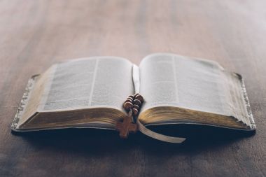 open holy bible and rosary with cross on wooden table   clipart