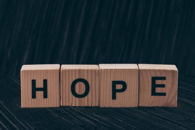 wooden cubes with word Hope on black table clipart