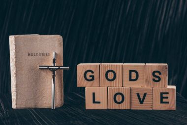 wooden cubes with words Gods Love and bible on black table clipart