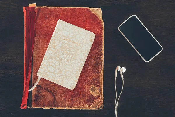 Κάτοψη Της Βίβλου Smartphone Και Ακουστικά Στο Ξύλινο Τραπέζι — Δωρεάν Φωτογραφία