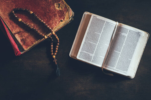 top view of open holy bible with rosary on table  