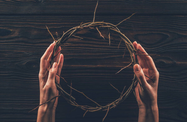 cropped image of woman holding crown of thorns in hands 