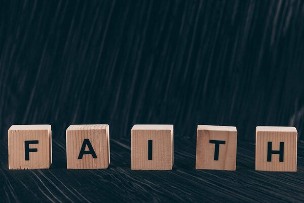 wooden cubes with word Faith on dark table