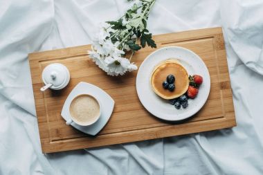 top view of breakfast in bed with delicious pancakes and coffee on wooden tray clipart