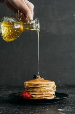 cropped shot of woman pouring maple syrup onto stack of freshly baked pancakes clipart