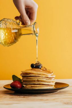 cropped shot of person pouring maple syrup onto stack of pancakes clipart