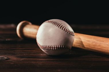 close-up view of white leather baseball ball and bat on wooden table clipart