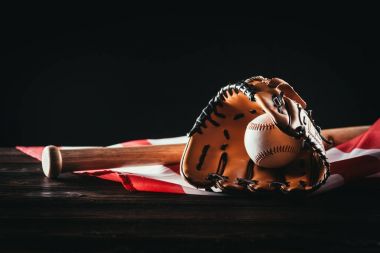 close-up view of baseball glove with ball and bat on wooden table and us flag on black clipart