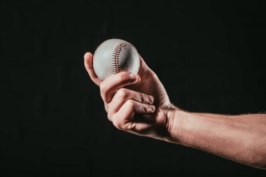 close-up partial view of male hand holding baseball ball isolated on black  clipart