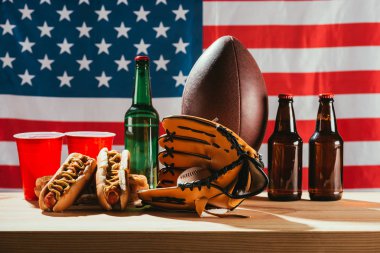 close-up view of beer with hot dogs and sport equipment with us flag behind   clipart