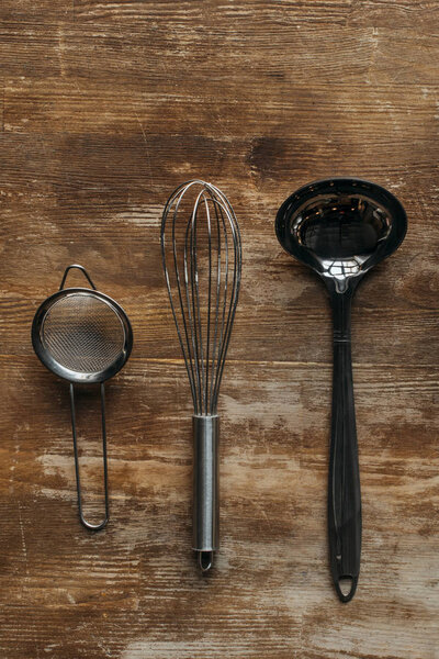 top view of metallic kitchen utensils on wooden table