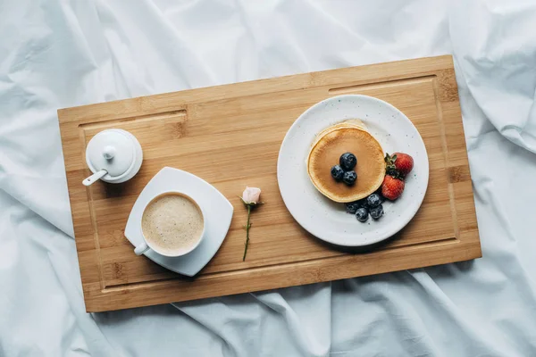 木製トレイに美味しいパンケーキとコーヒーとベッドでの朝食のトップ ビュー — ストック写真