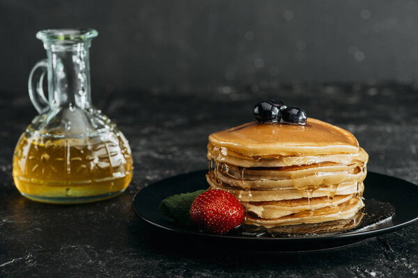stack of freshly baked pancakes poured with maple syrup