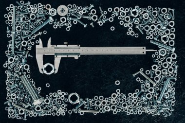 top view of metal vernier caliper, screws and clinchers on dark tabletop clipart