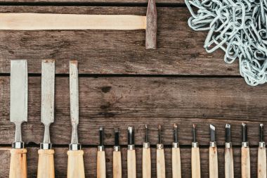 flat lay with chain, hammer and chisels for woodcraft on dark wooden tabletop clipart