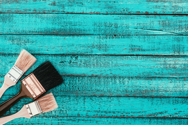 top view of arranged paint brushes for redecoration on blue wooden surface