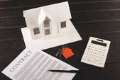 house buying concept with contract, keys, calculator and maquette over wooden table